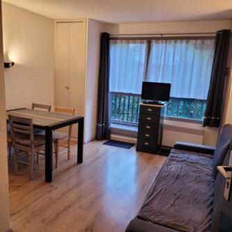 - un salon avec une table, un canapé et une télévision dans l'établissement Valloire - Appartement au pied des pistes, à Valloire