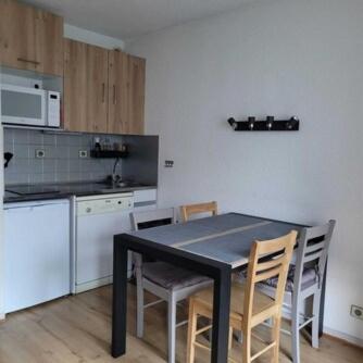 une cuisine avec une table et des chaises noires ainsi qu'un comptoir dans l'établissement Valloire - Appartement au pied des pistes, à Valloire