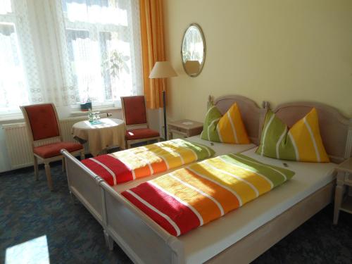 ein Schlafzimmer mit einem Bett mit bunten Kissen in der Unterkunft Pension Fürstenhof in Bad Elster