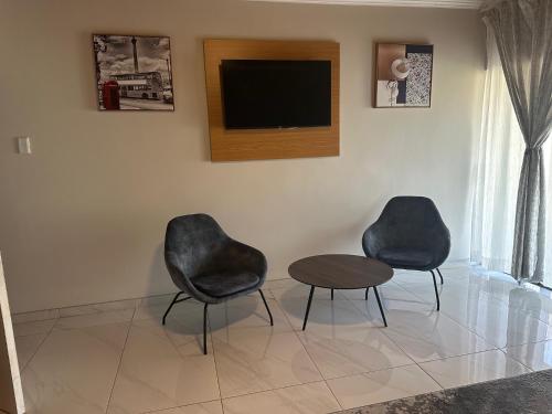 two chairs and a table in a room with a tv at Vilanculos Guesthouse in Brakpan