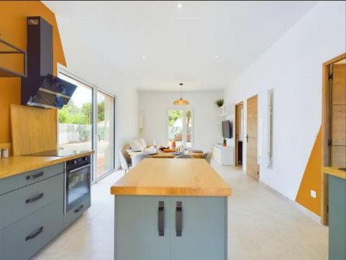 une cuisine avec des placards blancs et un îlot de cuisine dans l'établissement Maison - 8 à 10 personnes les Grenettes, à Sainte-Marie de Ré