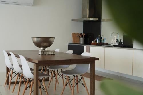 a kitchen with a wooden table and white chairs at The Beach Residence in Koh Samui 