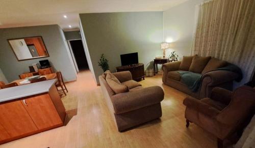 una sala de estar con un sofá y una silla en Aub's Place, en Gqeberha