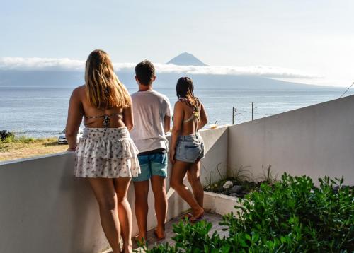 three people standing on a wall looking at the ocean at Casa dos Terreiros Oceanfront Villa in Manadas