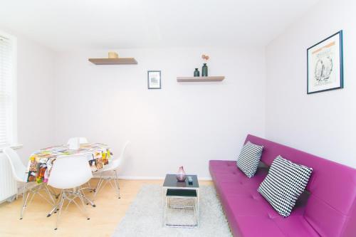 a living room with a purple couch and a table at Maple Street Apartments in London