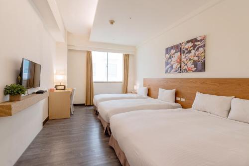a hotel room with three beds and a flat screen tv at Guide Education Culture Hotel Kaohsiung Museum of Fine Arts in Kaohsiung