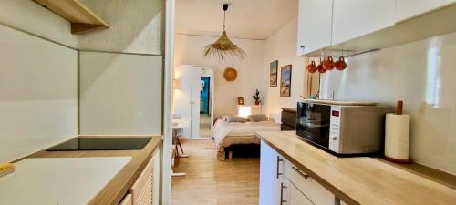 - une cuisine équipée d'un four micro-ondes et un lit dans une chambre dans l'établissement Joli studio à 1 minute de la mer, à Toulon