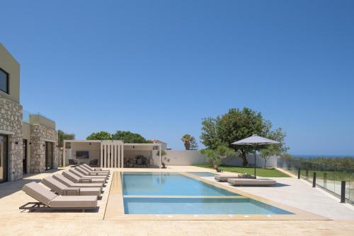 a pool with lounge chairs and an umbrella at Elia Villa, with Pool, SeaViews & Iconic Design, By ThinkVilla in Astérion