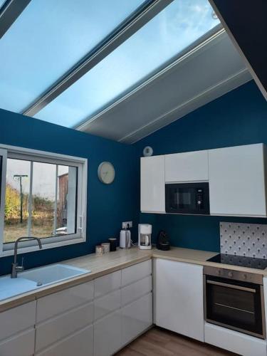 a kitchen with white cabinets and a large window at Maison cosy Val André avec SPA in Pléneuf-Val-André