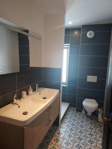 a bathroom with a sink and a toilet and a mirror at Maison cosy Val André avec SPA in Pléneuf-Val-André