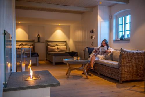 a woman sitting on a couch in a living room at Hotel Rusthållargården in Arild