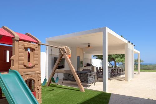a playground with a slide and a play house at Elia Villa, with Pool, SeaViews & Iconic Design, By ThinkVilla in Astérion