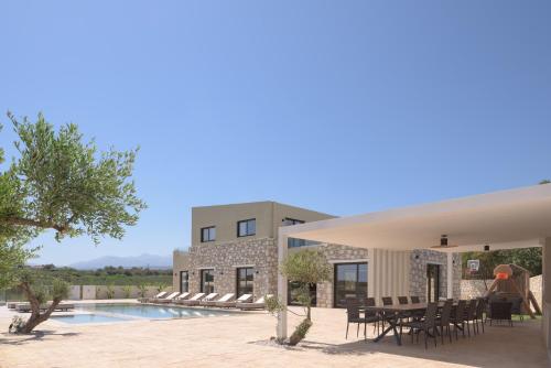 a patio with a table and chairs next to a pool at Elia Villa, with Pool, SeaViews & Iconic Design, By ThinkVilla in Astérion