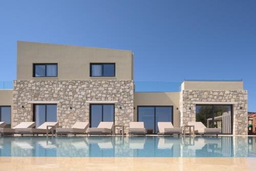 a swimming pool with lounge chairs and a building at Elia Villa, with Pool, SeaViews & Iconic Design, By ThinkVilla in Astérion