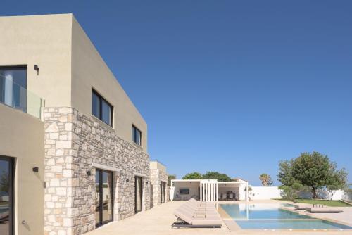 a house with a swimming pool next to a building at Elia Villa, with Pool, SeaViews & Iconic Design, By ThinkVilla in Astérion