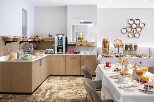 a dining room with two tables and a kitchen at H&ocirc;tel Eliseo in Lourdes