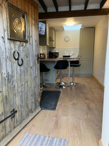 una cucina con una parete in legno e due sgabelli da bar di Cosy 3-Bed Apartment on Exmoor a Minehead