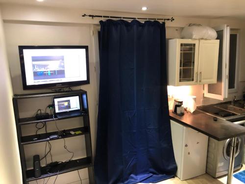 une cuisine avec un rideau bleu et une télévision dans l'établissement Appartement quartier Sainte Marthe, à Paris