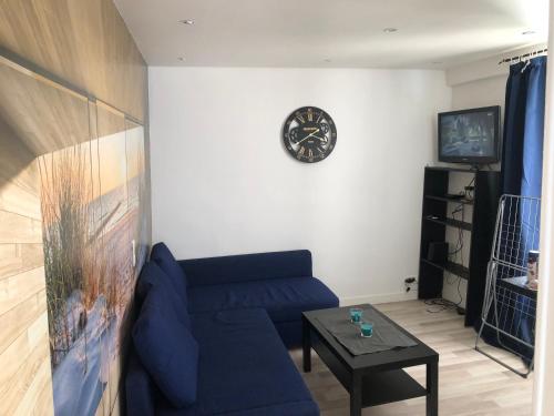 un salon avec un canapé bleu et un réveil dans l'établissement Appartement quartier Sainte Marthe, à Paris