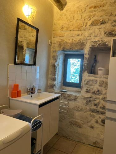 La salle de bains en pierre est pourvue d'un lavabo et d'une fenêtre. dans l'établissement gite de Pierrebrune, à Issirac