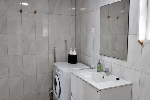 a bathroom with a washing machine and a sink at Casa dos Terreiros Oceanfront Villa in Manadas