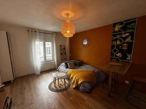 a bedroom with a bed and a table and a chandelier at Le Petit phucket - centre ville - wifi in Niort