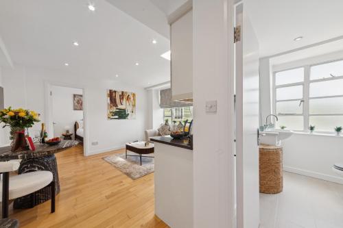 a kitchen and living room with white walls and wood floors at Nell Gwynn Chelsea Accommodation in London