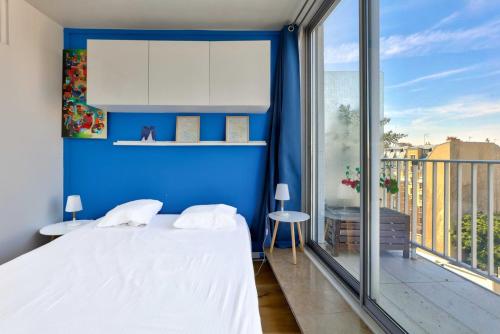 - une chambre bleue avec un lit et une grande fenêtre dans l'établissement GuestReady - Charmant Séjour avec Vue Panoramique, à Paris