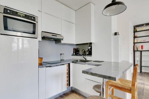 une cuisine blanche avec un évier et un micro-ondes dans l'établissement GuestReady - Studio Idéal pour 2 au cœur de Paris, à Paris