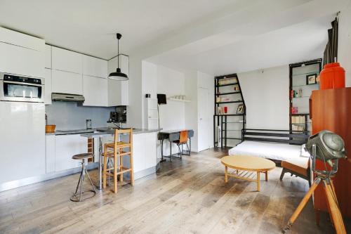 une chambre avec un lit et une cuisine avec des placards blancs dans l'établissement GuestReady - Studio Idéal pour 2 au cœur de Paris, à Paris