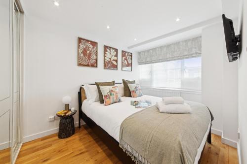 a bedroom with a bed with white sheets and a window at Nell Gwynn Chelsea Accommodation in London