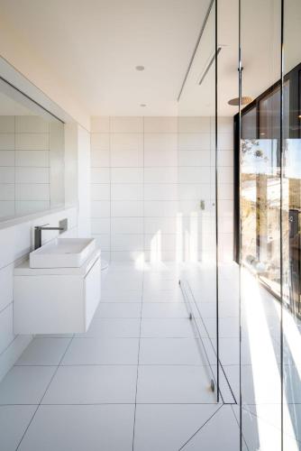 a white bathroom with a sink and a glass wall at Mountain Top Snug, Studio Itas in Snug