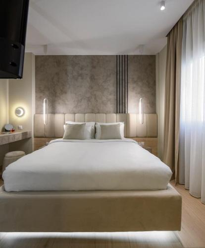 a bedroom with a large white bed and a television at Aristotelian Virtues - Elpida in Thessaloniki