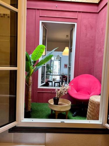 une vue de la fenêtre d'une pièce avec une chaise rose dans l'établissement Appartement Cosy, à Bordeaux