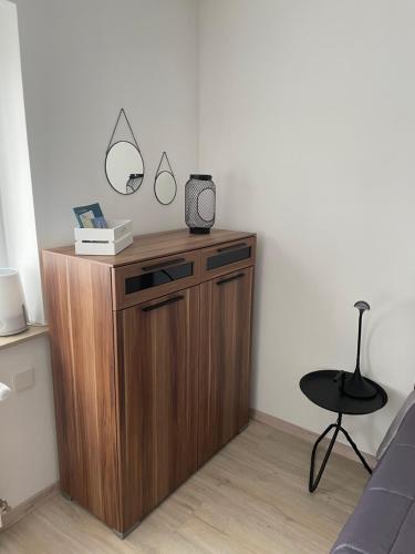 a wooden cabinet with a mirror and a chair in a room at Appartement Hygge J65 in Elchingen
