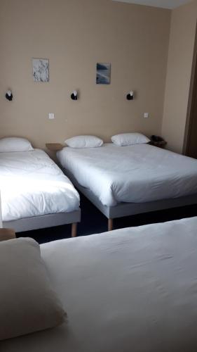 three beds in a room with white sheets at Logis hotel Noemys Gradignan in Gradignan