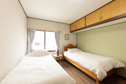a bedroom with two beds and a window at Guest House 来夢 in Otaru