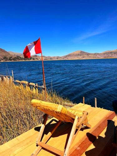 a flag on a wooden bench next to a body of water at Uros Maya Lodge in Puno
