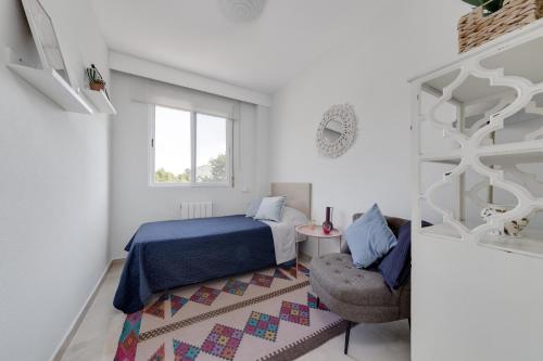 a bedroom with a bed and a chair and a window at Apartamentos Oasis in Albir
