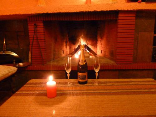 a bottle of champagne and two wine glasses in front of a fireplace at Theasis suites-Ορεινή Φιλοξενία in Kato Trikala Korinthias