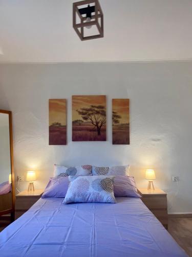 a bedroom with a blue bed with three paintings on the wall at Beverly house in Kriopigi