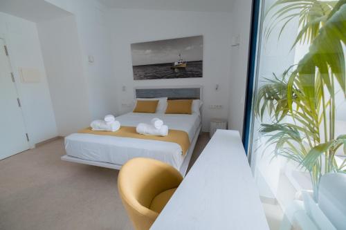 a bedroom with a bed and a yellow chair at Hotel Boutique Es Blau in Cadaqués