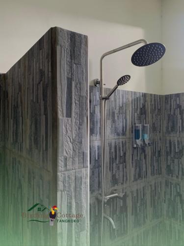 a shower with a shower head in a bathroom at Birding Cottage Tangkoko in Rinondoran