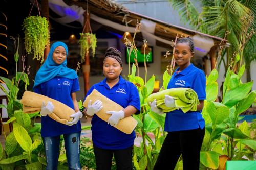 three women in blue shirts standing in a garden at Ondo House in Nungwi