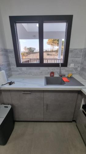 une cuisine avec un évier et une fenêtre dans l'établissement Bel Appartement F3 proche de la plage, à Pietrosella