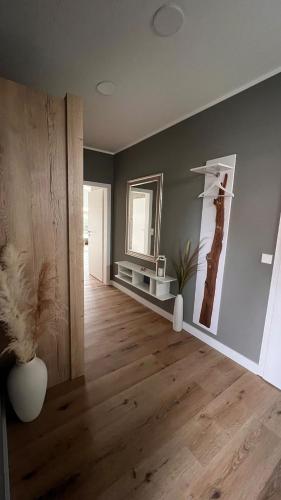 a living room with wooden floors and a mirror at Winkelschiffchen II mit Sauna in Juist