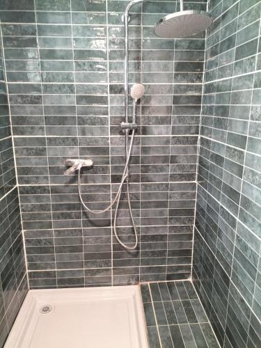 La salle de bains carrelée est pourvue d'une douche avec un tuyau. dans l'établissement Loft avec chambre, tout confort pour les jo ou visiter Paris, à Aubervilliers