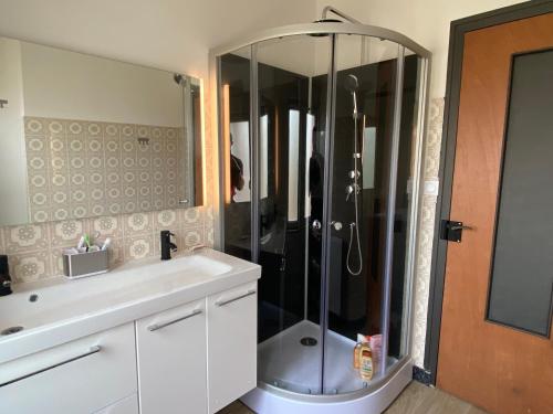 a bathroom with a shower with a sink and a counter at La musique des Vacances in Portbail