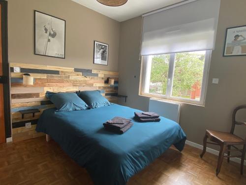 a bedroom with a blue bed with two towels on it at La musique des Vacances in Portbail