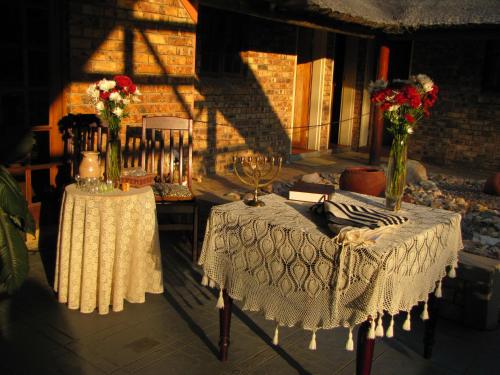 two tables with vases of flowers on them at SERENITY Du Bois Lodge in Marloth Park